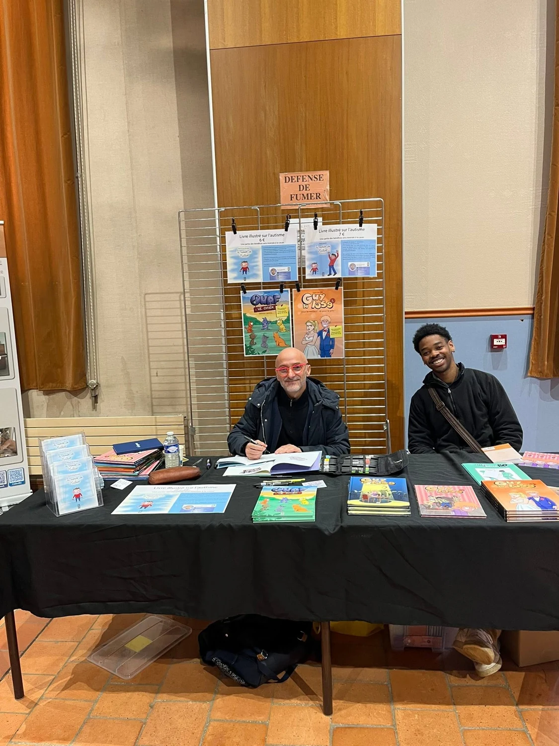 Deux personnes derrière un stand de livres au salon 2026